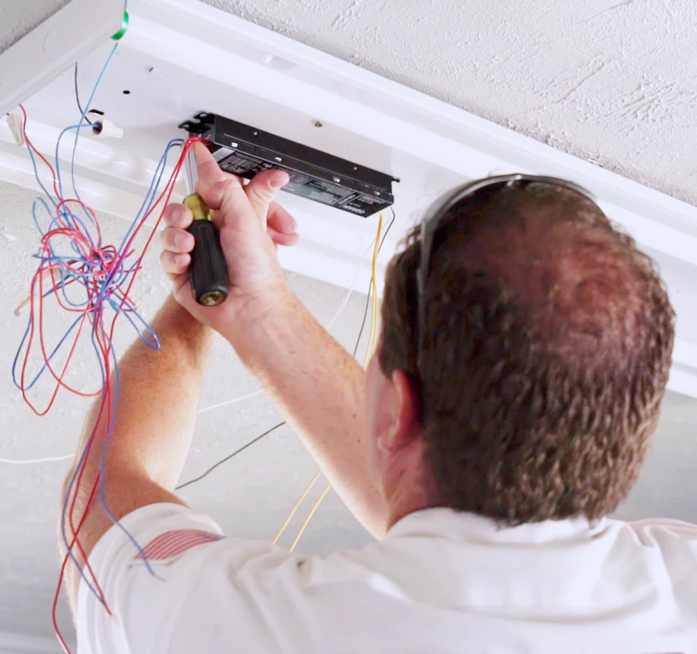 Any Hour Electrician works on rewiring a fluorescent light fixture.